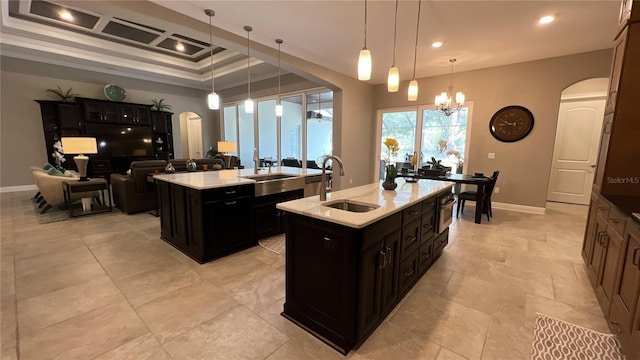 kitchen with a chandelier, pendant lighting, light tile floors, a center island with sink, and sink