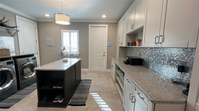 kitchen featuring light tile floors, a kitchen island, hanging light fixtures, washer and clothes dryer, and backsplash