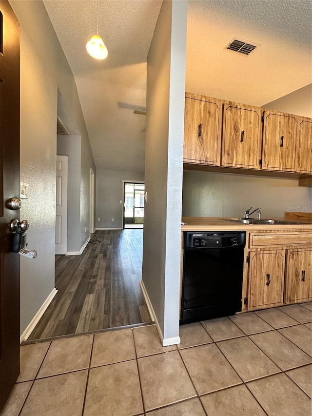 kitchen with black dishwasher, a textured ceiling, hanging light fixtures, and light hardwood / wood-style floors