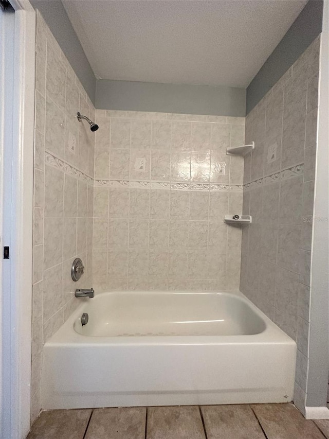 bathroom with tile flooring, tiled shower / bath combo, and a textured ceiling