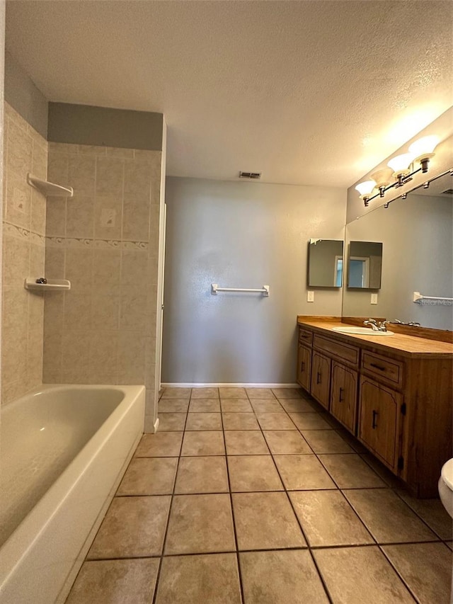 full bathroom featuring toilet, oversized vanity, a textured ceiling, tiled shower / bath, and tile flooring