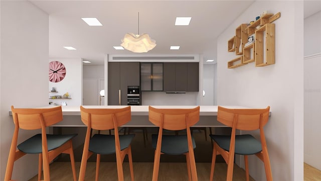 kitchen featuring hanging light fixtures, hardwood / wood-style floors, kitchen peninsula, and a breakfast bar area