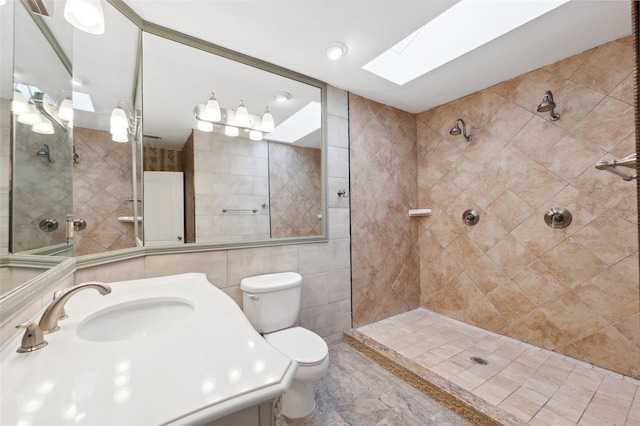 bathroom featuring tile walls, toilet, a tile shower, a skylight, and tile flooring