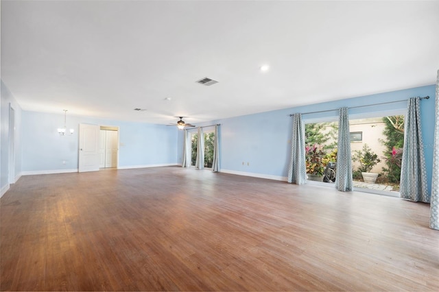 unfurnished living room with a healthy amount of sunlight, ceiling fan with notable chandelier, and light hardwood / wood-style flooring