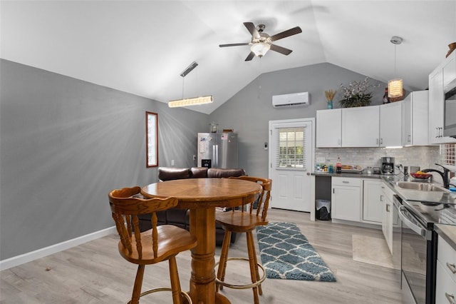 kitchen with appliances with stainless steel finishes, hanging light fixtures, white cabinetry, and a wall mounted AC