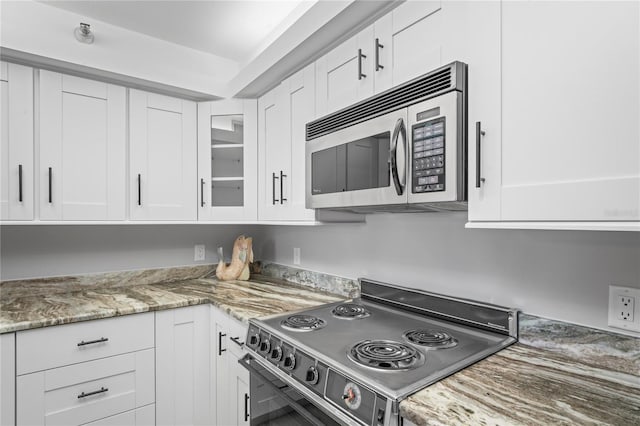 kitchen featuring stone counters, white cabinetry, and electric stove