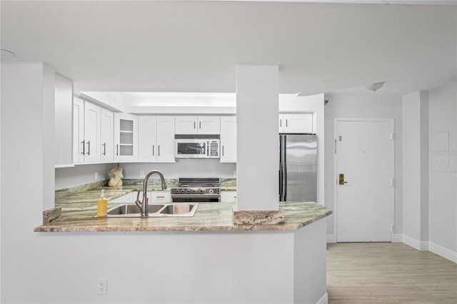 kitchen featuring sink, appliances with stainless steel finishes, light stone countertops, white cabinets, and kitchen peninsula