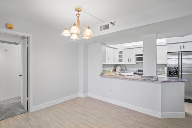 kitchen featuring pendant lighting, sink, white cabinets, kitchen peninsula, and stainless steel refrigerator with ice dispenser