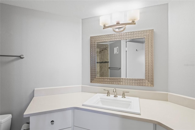 bathroom featuring vanity, a tile shower, and toilet