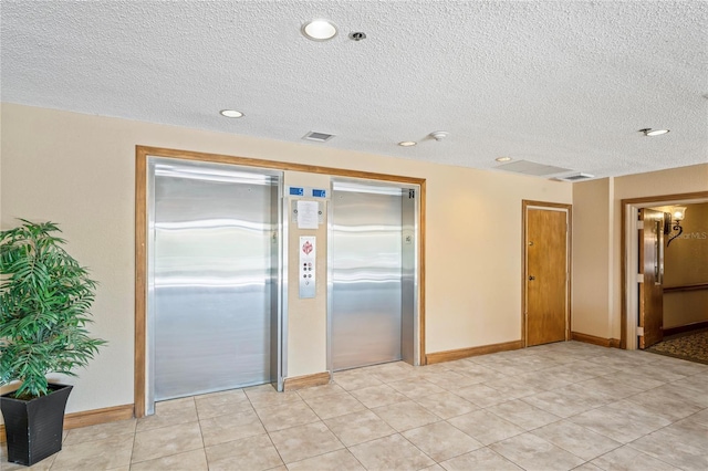 interior space featuring light tile patterned floors, a textured ceiling, and elevator