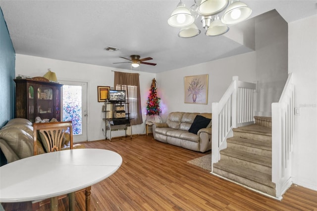 living room featuring wood-type flooring and ceiling fan with notable chandelier