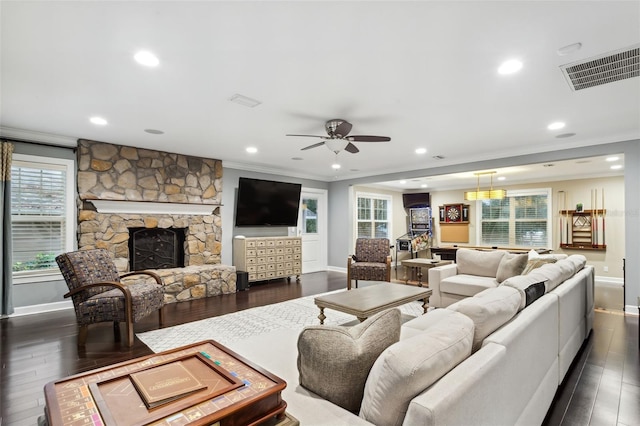 living room featuring dark hardwood / wood-style floors, ceiling fan, crown molding, and a fireplace