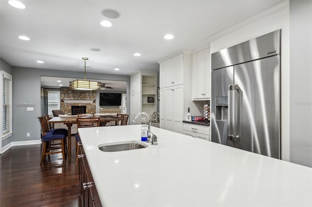 kitchen with sink, hanging light fixtures, dark hardwood / wood-style floors, stainless steel built in fridge, and white cabinets