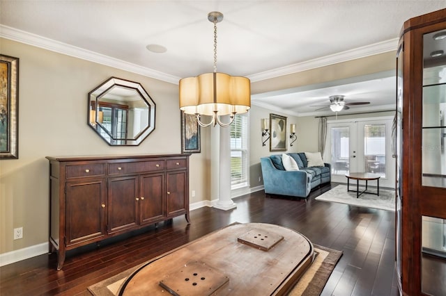 interior space featuring french doors, decorative columns, ceiling fan with notable chandelier, dark wood-type flooring, and crown molding