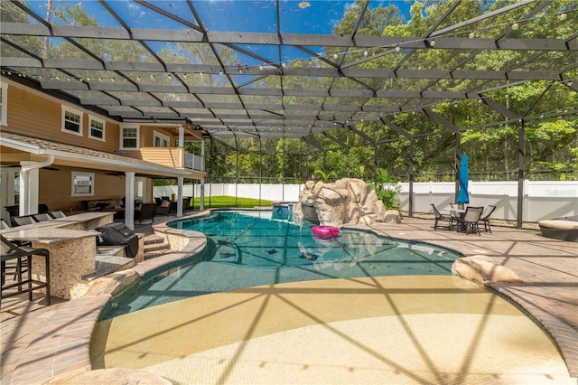 view of pool featuring a patio, glass enclosure, and an outdoor bar