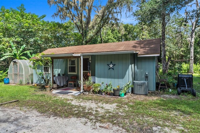 view of front of house featuring a front lawn, central AC, and an outdoor structure