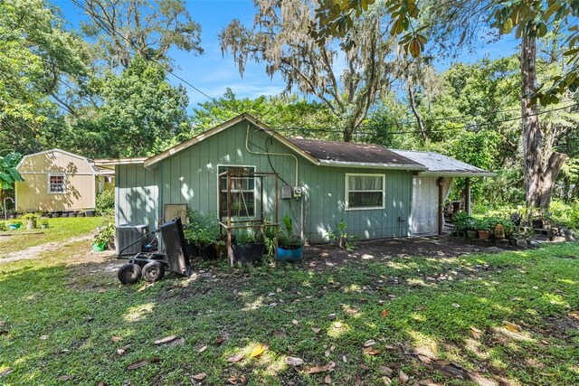 view of front of property featuring central AC, a shed, and a front lawn