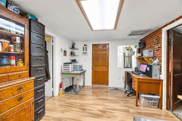 office space featuring brick wall and light hardwood / wood-style flooring