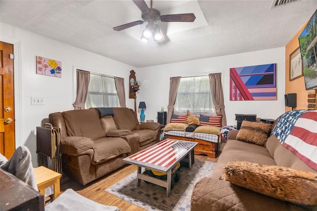 living room featuring wood-type flooring, a textured ceiling, and ceiling fan