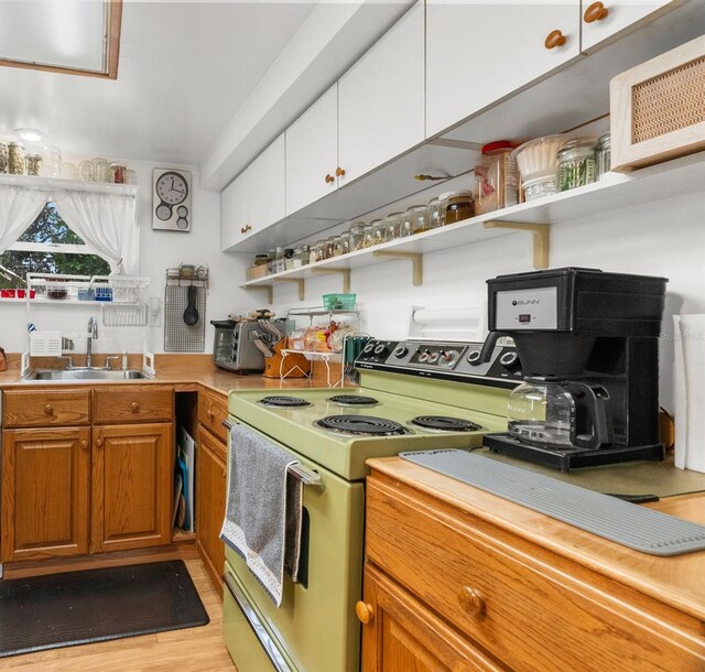 kitchen featuring sink, light hardwood / wood-style floors, white cabinets, and electric stove