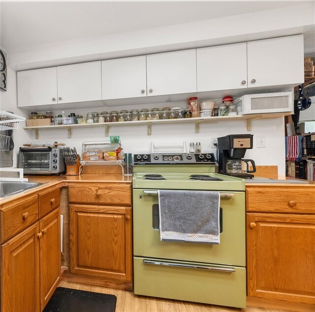 kitchen featuring white cabinets, light hardwood / wood-style flooring, and white electric range