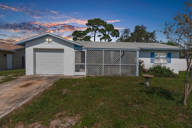 single story home featuring a garage and a lawn