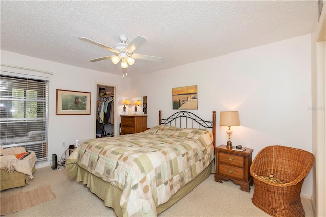 carpeted bedroom featuring a textured ceiling, a spacious closet, a closet, and ceiling fan