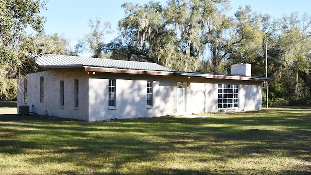 rear view of property with cooling unit and a lawn