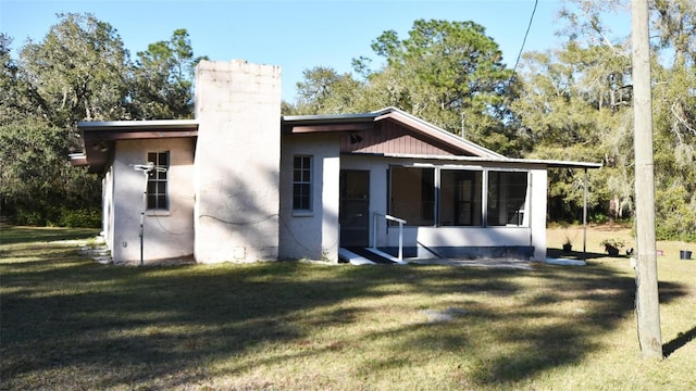 rear view of house featuring a lawn and a sunroom