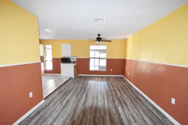 unfurnished living room featuring ceiling fan, dark hardwood / wood-style floors, and a textured ceiling