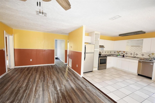 kitchen featuring appliances with stainless steel finishes, light wood-type flooring, sink, and white cabinetry