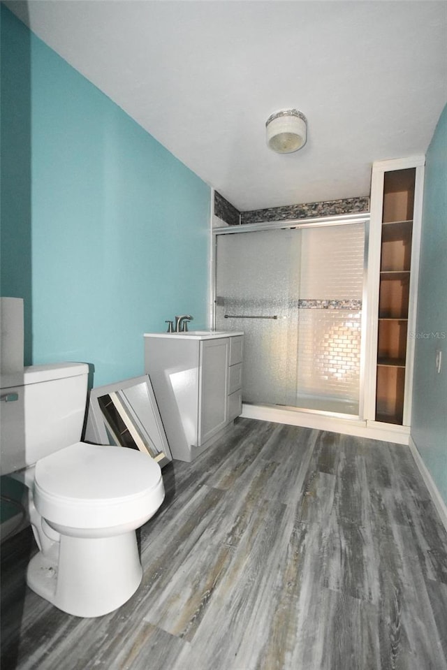 bathroom with hardwood / wood-style floors, a shower with door, toilet, built in shelves, and sink