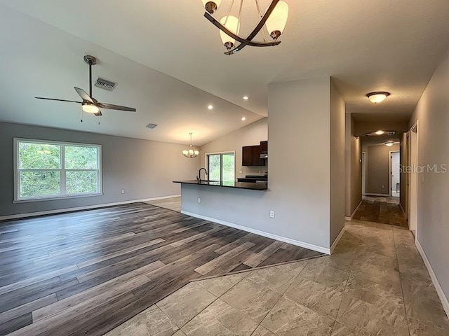 unfurnished living room featuring vaulted ceiling, sink, ceiling fan with notable chandelier, and light hardwood / wood-style flooring