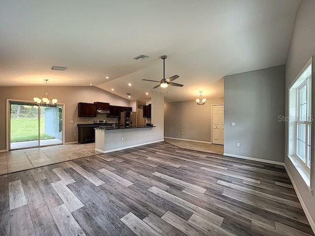 kitchen with lofted ceiling, stainless steel fridge, dark brown cabinetry, kitchen peninsula, and light wood-type flooring