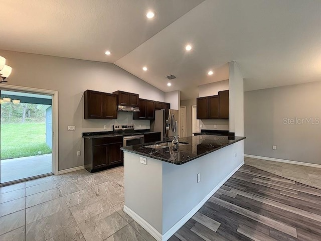 kitchen featuring vaulted ceiling, appliances with stainless steel finishes, sink, dark stone counters, and kitchen peninsula