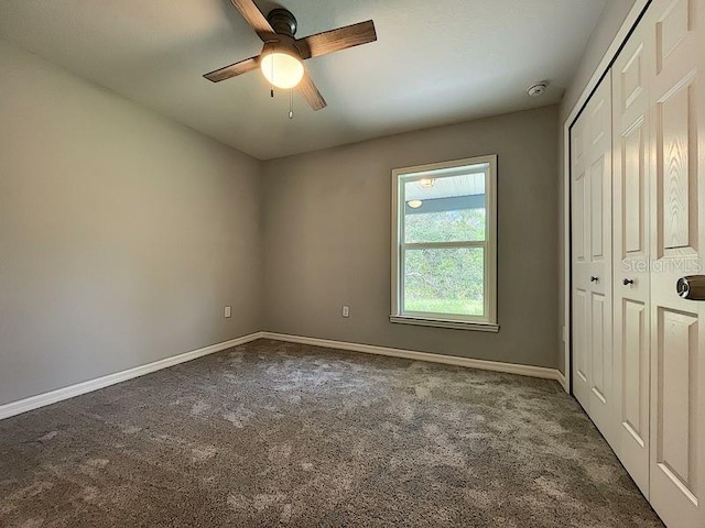 unfurnished bedroom featuring a closet, ceiling fan, and dark colored carpet