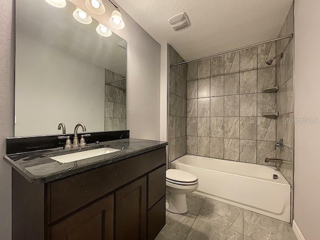 full bathroom featuring vanity, toilet, tiled shower / bath combo, and a textured ceiling