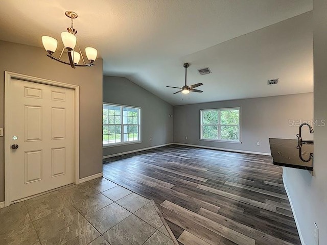 foyer entrance with vaulted ceiling, plenty of natural light, dark wood-type flooring, and ceiling fan with notable chandelier