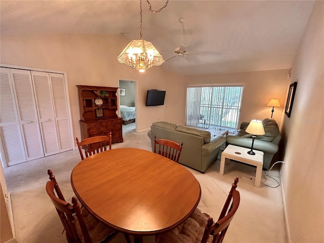 dining room featuring light carpet, vaulted ceiling, and ceiling fan with notable chandelier