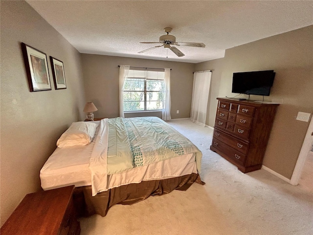 bedroom featuring light carpet, ceiling fan, and a textured ceiling