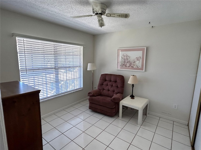 sitting room with a textured ceiling, ceiling fan, and light tile flooring