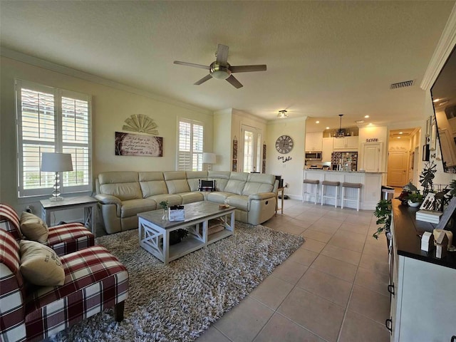 tiled living room with a textured ceiling, plenty of natural light, crown molding, and ceiling fan