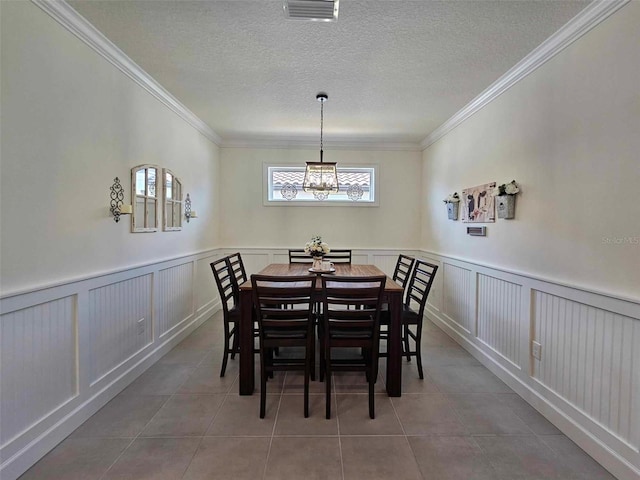 tiled dining area featuring crown molding and an inviting chandelier