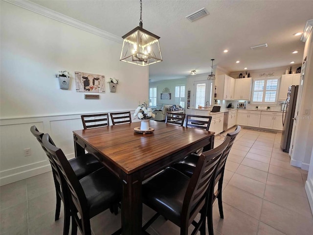 tiled dining room with crown molding, sink, and a chandelier