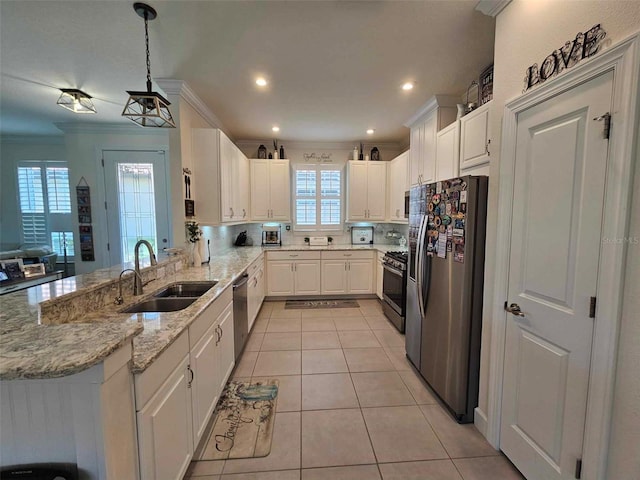 kitchen with appliances with stainless steel finishes, ornamental molding, sink, decorative light fixtures, and white cabinetry