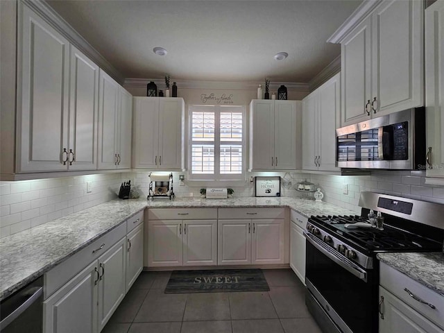 kitchen featuring white cabinetry, crown molding, dark tile patterned flooring, and appliances with stainless steel finishes