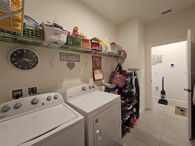 clothes washing area featuring visible vents, separate washer and dryer, light tile patterned flooring, baseboards, and laundry area