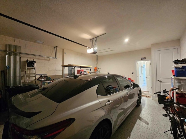 garage with a garage door opener and concrete block wall