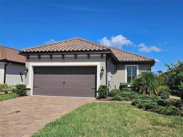 mediterranean / spanish-style house with stucco siding, decorative driveway, an attached garage, and a tiled roof