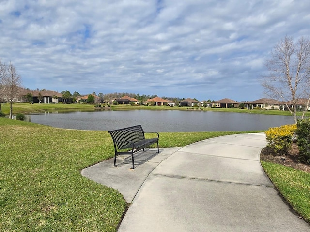 view of home's community with a residential view, a yard, and a water view